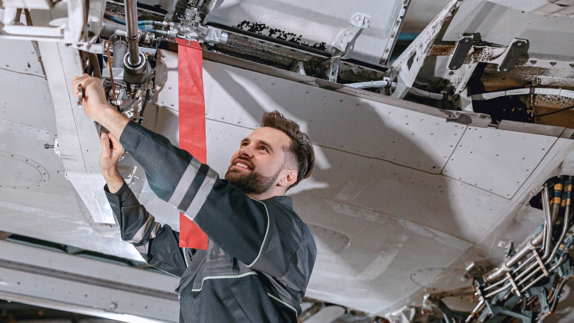 Técnico de mantenimiento aeronáutico con mono azul realizando una inspección rutinaria del tren de aterrizaje de una aeronave.
